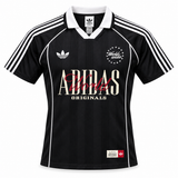 Camiseta Adidas World Wide negra con cuello polo, el trébol y ADIDAS en letras grandes al pecho