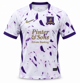 Camiseta del AFC Richmond blanca con pinceladas moradas, el escudo del galgo y Pinter & Sons en dorado al pecho