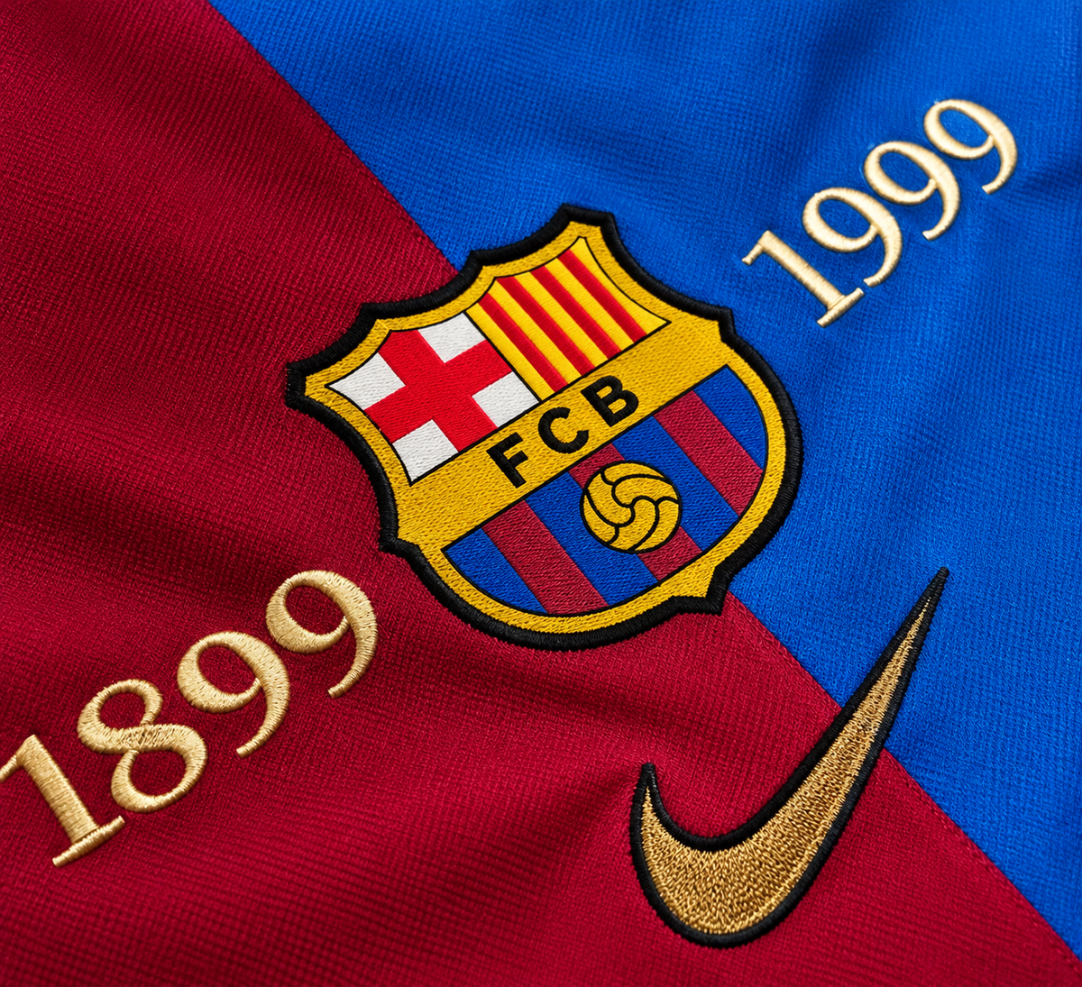 Escudo del FC Barcelona y las fechas 1899 y 1999 en dorado sobre la camiseta partida en granate y azul