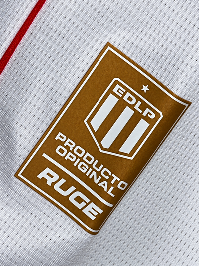 Etiqueta dourada EDLP da Ruge na parte de baixo da camisa branca do Estudiantes