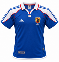 Camiseta retro azul de Japón 2000 con cuello polo blanco, hombros blancos y el escudo de la JFA