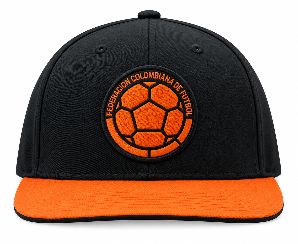 Gorra plana negra de la Selección Colombia con visera naranja y el escudo de la Federación en naranja al frente, foto de estudio