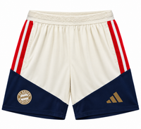 Pantaloneta crema del Bayern Múnich con paneles azul marino abajo, rayas rojas a los lados y escudo dorado