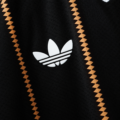 Detalle del trébol blanco sobre la tela negra de la camiseta de Alemania tercera 2026, entre las rayas de rombos dorados