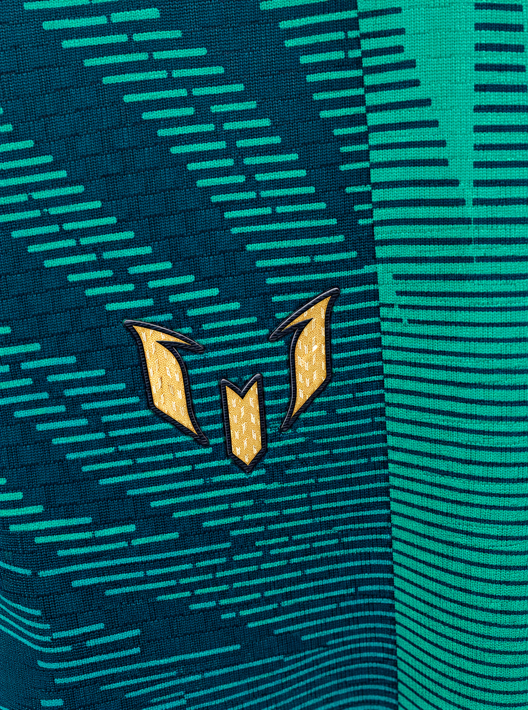 Detalle del logo de Messi en dorado sobre el tejido verde de la camiseta de Argentina