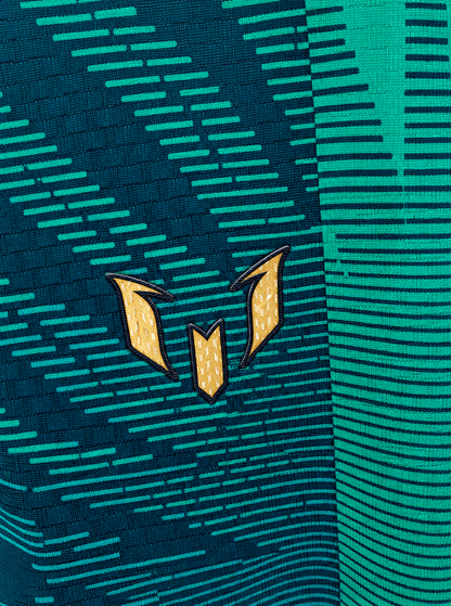 Detalle del logo de Messi en dorado sobre el tejido verde de la camiseta de Argentina