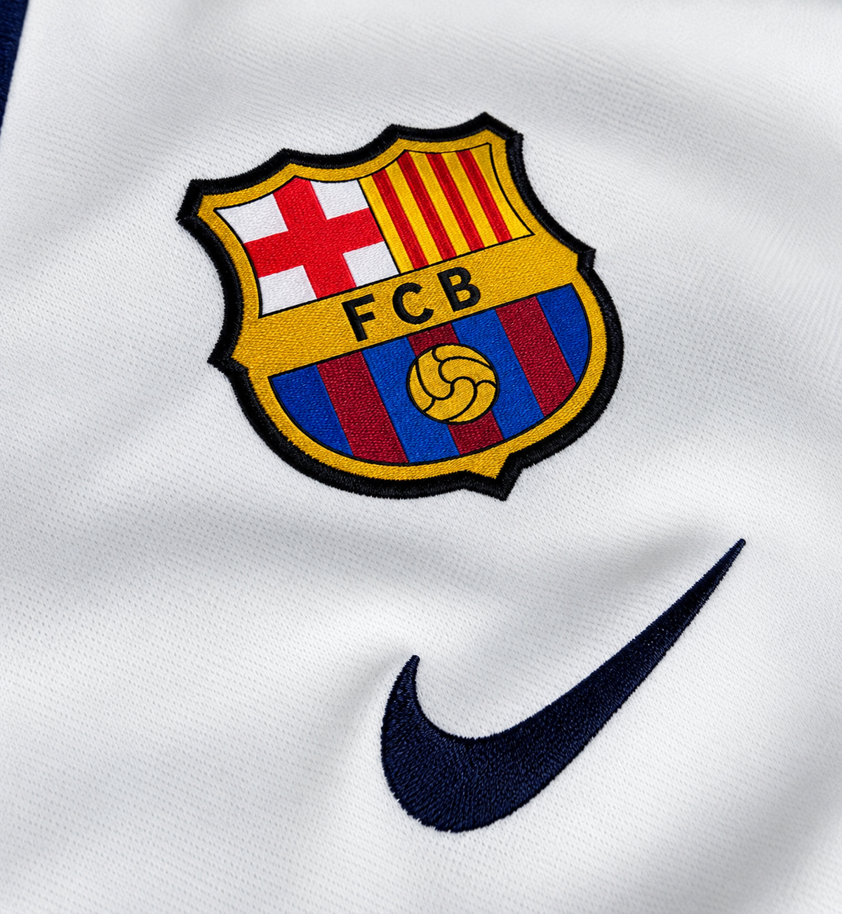 Escudo del FC Barcelona termosellado sobre la camiseta retro blanca, con el logo de la marca en azul oscuro al lado
