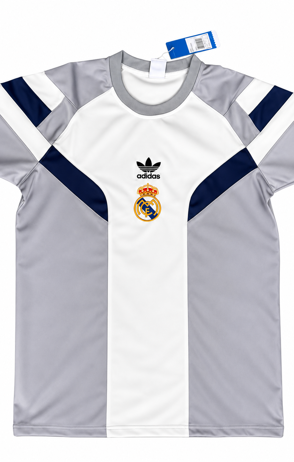 Camiseta retro del Real Madrid blanca con paneles grises y azul oscuro en hombros y costados, escudo dorado y trébol de la marca